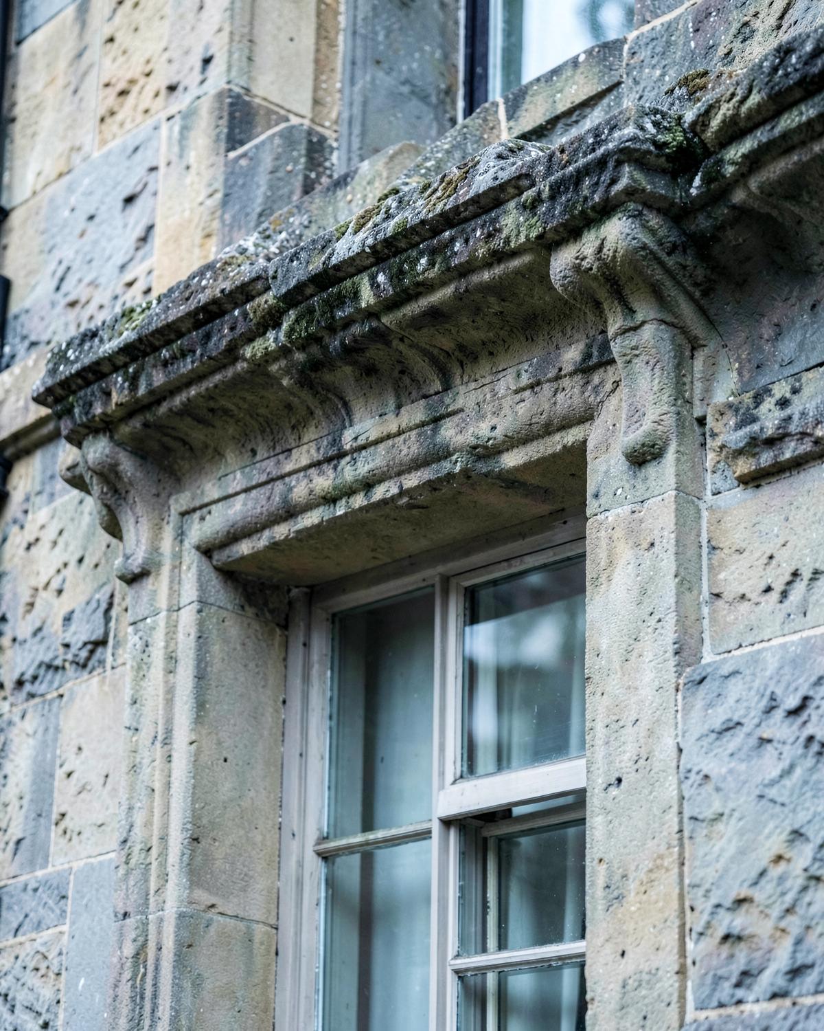Carved sandstone lintel above a sash window on a period Liverpool building